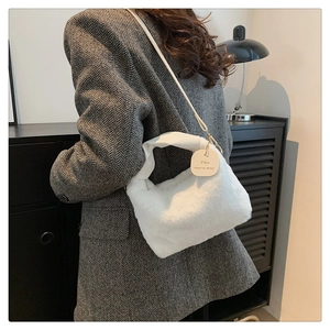 Détail de la texture peluche blanche et du pendentif rond sur le sac à main tendance