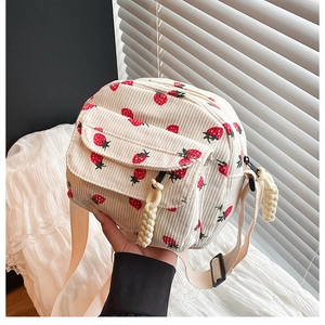Close-up of white corduroy crossbody bag featuring sweet red strawberry prints and textures