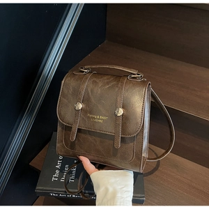 Detail of vintage dark brown faux leather bag with metal buckles on a book
