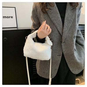 Détail du sac à main en peluche blanche avec poignées en cuir et boucles métalliques