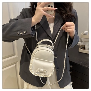 Close-up of creamy white bow backpack with lace trim and elegant metal chain strap
