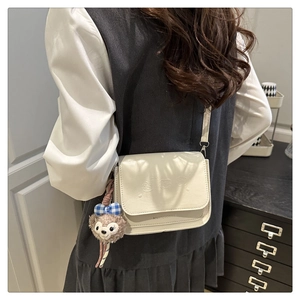 Détail du sac bandoulière blanc crème avec têtes d'ours en relief et pendentif en peluche