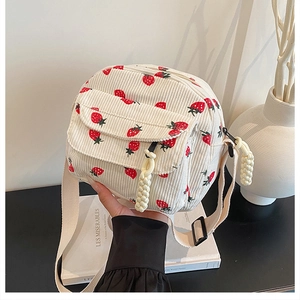 Detailed texture of corduroy strawberry crossbody bag with rope zipper pull and front pocket