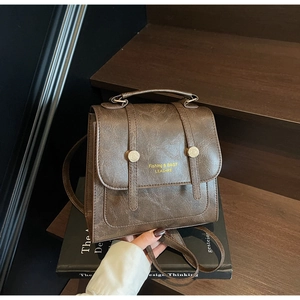 Detailed macro view of vintage brown faux leather texture and gold hardware on the backpack
