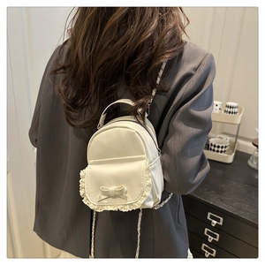 Dettaglio mini zaino bianco con pizzo delicato e decorazione con fiocco