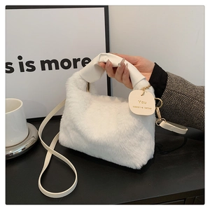 Détail du sac à main en peluche blanche avec étiquette ronde et bandoulière en cuir