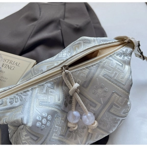 Detailed view of jacquard dumpling bag with floral patterns and marble bead zipper puller