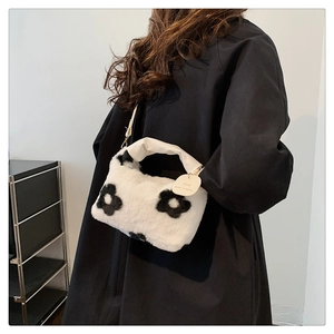 Détail d'un sac à main en peluche à motif floral noir et blanc avec large anse blanche
