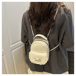 Detailansicht weißer Mini-Rucksack mit Spitzenbesatz, Schleife und Metallkettenriemen