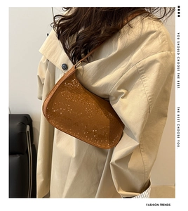 Detailed view of brown snakeskin embossed leather shoulder bag styled with a beige coat