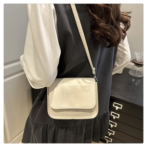 Détail du sac bandoulière blanc avec trois oursons gaufrés et une texture en cuir