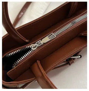 Close-up of smooth silver metal zipper on premium brown leather handbag for women