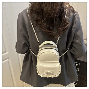 Rear view of a white mini leather backpack with delicate lace trim and a cute bow detail
