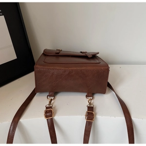 Detail view of reinforced stitching and metal hardware on dark brown vintage backpack