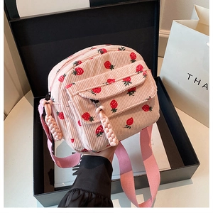 Detail of pink corduroy crossbody bag with strawberry patterns and zipper closure
