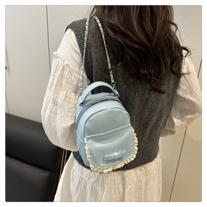 Primo piano di un mini zaino azzurro con fiocco e finiture in pizzo bianco eleganti