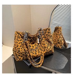 Close-up of leopard print tote bag with gold chain strap and pearl charm on a table