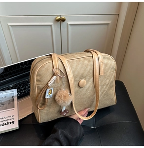 Close-up of brown suede tote bag with decorative pocket and plush charm detail