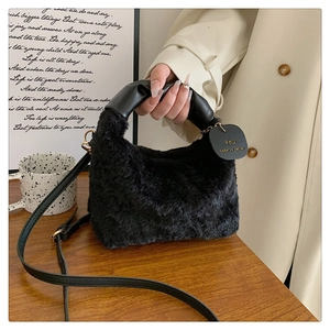 Gros plan du sac à main en peluche noire avec poignée en cuir et étiquette décorative