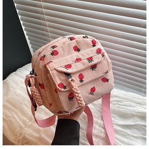 Close-up of pink corduroy mini crossbody bag featuring red strawberry prints and double zippers