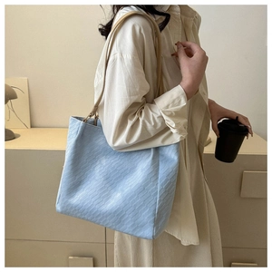 Detailed texture of a light blue tote bag with a brick-pattern embossed finish