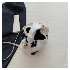 Détail du sac seau en peluche à motif vache avec poignée volantée et fine bandoulière