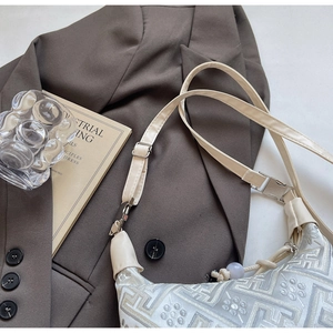 Detailed close-up of intricate white floral embroidery on a vintage style crossbody bag