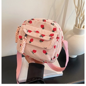 Detail view of pink corduroy crossbody bag featuring cute red strawberry embroidery texture