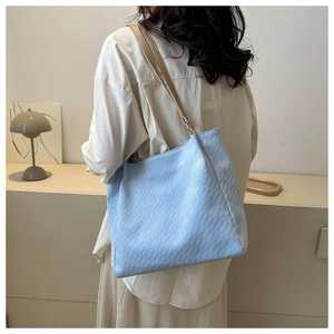 Detail of light blue textured tote bag with woven pattern and beige shoulder straps