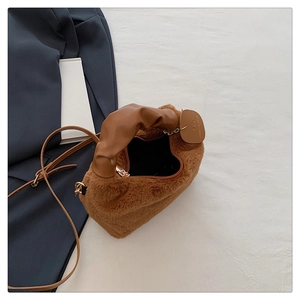 Détail d'un sac à main en peluche marron avec anse plissée et finitions métalliques dorées