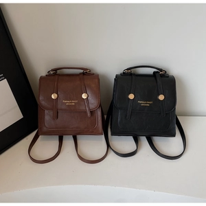 Detail of vintage mini leather backpacks in brown and black with gold metal accents
