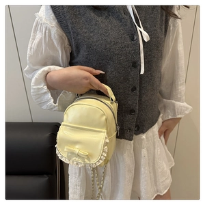 Detailansicht der cremegelben PU-Ledertasche mit Schleife und weißer Spitzenverzierung