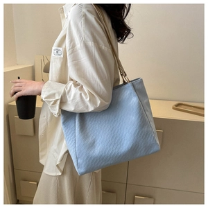 Detail of light blue textured tote bag showing golden ring buckle and woven fabric finish