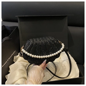 Detail of black shell-shaped handbag with snake pattern leather and pearl handle decoration