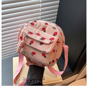Detail of pink corduroy crossbody bag with strawberry print and woven zipper pull