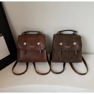 Close-up of retro PU leather backpacks in dark brown and olive green with gold lettering