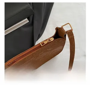 Detailed macro view of smooth gold zipper and snake-embossed leather on brown bag