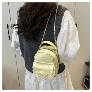 Detail eines cremegelben Mini-Rucksacks mit Spitze und Schleife, getragen am Model