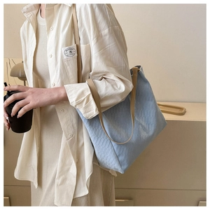 Close-up of light blue quilted tote bag with brown leather straps worn by a model
