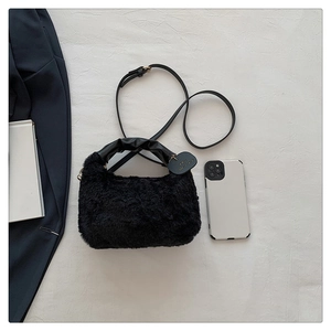 Détail d'un sac à main en peluche noire avec poignée en cuir froncé et fine bandoulière