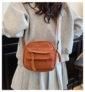 Gros plan d'un sac bandoulière en velours côtelé caramel avec tirette en corde tissée