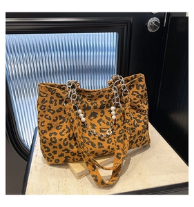 Detail of leopard print corduroy tote bag featuring silver chain and pearl flower charms