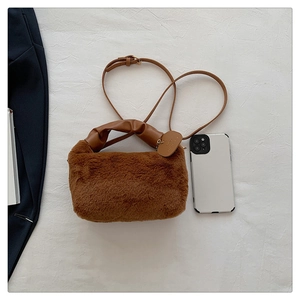 Détail du sac à main en peluche marron avec anses en cuir et smartphone pour comparer la taille