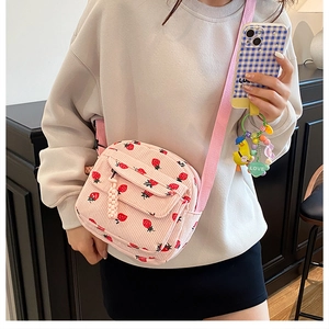 Close-up of pink corduroy crossbody bag with strawberry print and cute duck charm