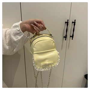 Detailansicht der gelben Mini-Rucksack-Tasche mit Spitze, Schleife und Goldkette