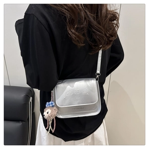 Détail du sac bandoulière argenté mat avec gaufrage de dessin animé et ours peluche
