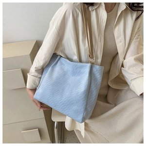Close-up of light blue tote bag featuring premium woven leather texture and soft finish