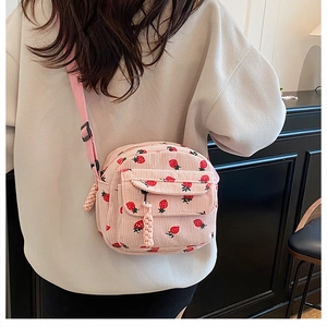 Pink corduroy crossbody bag with strawberry print shown on model from back view