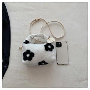 Détail du sac à main en peluche blanche avec fleurs noires et poignée en cuir