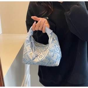 Detailed close-up of blue silk embroidery bag with geometric floral patterns and bead charm